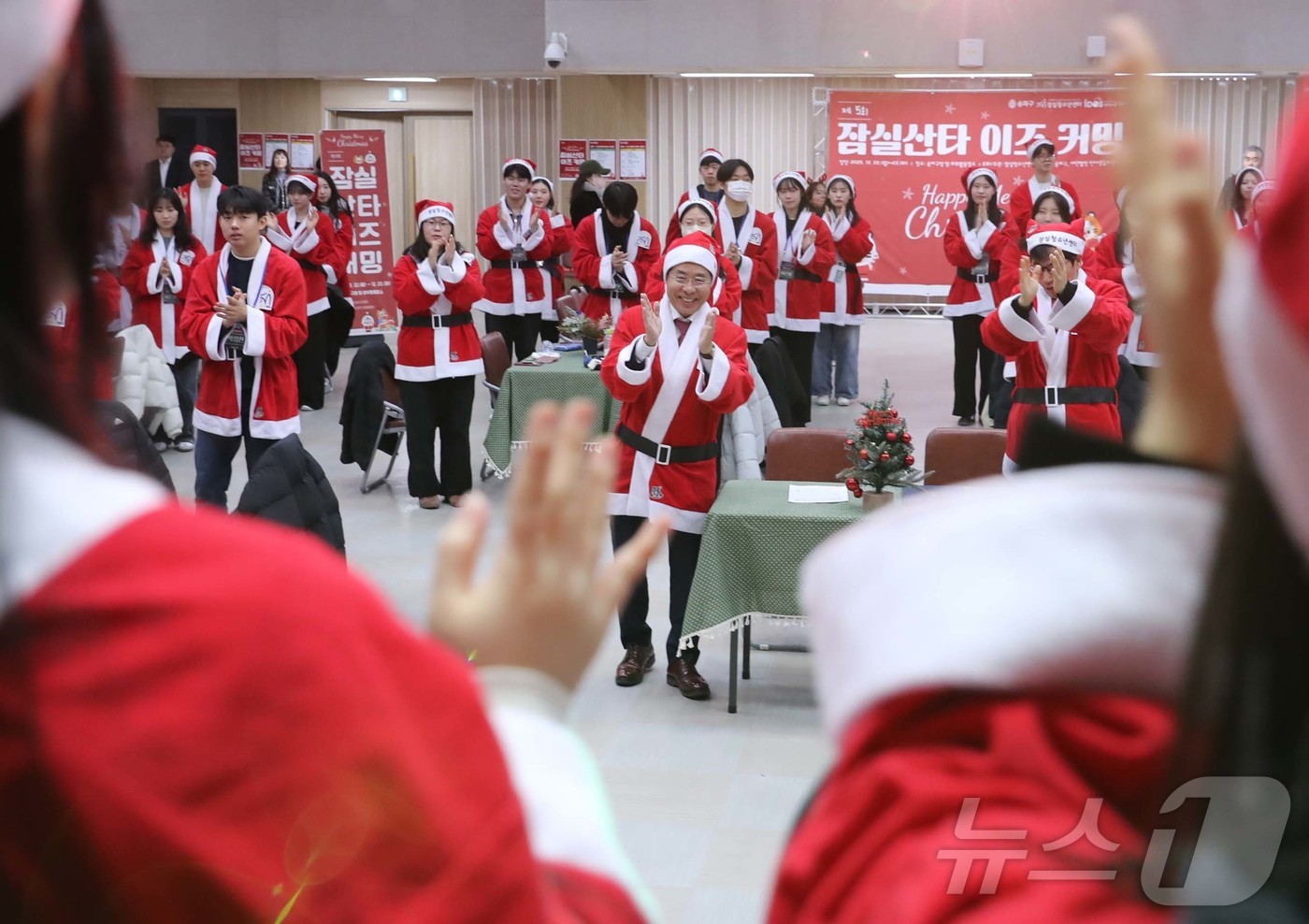 (서울=뉴스1) = 서강석 송파구청장이 23일 구청 대강당에서 열린 잠실산타이즈 커밍 출정식에서 산타 복장을 한 봉사자들과 노래를 부르며 율동을 하고 있다.송파구는 크리스마스를 앞 …