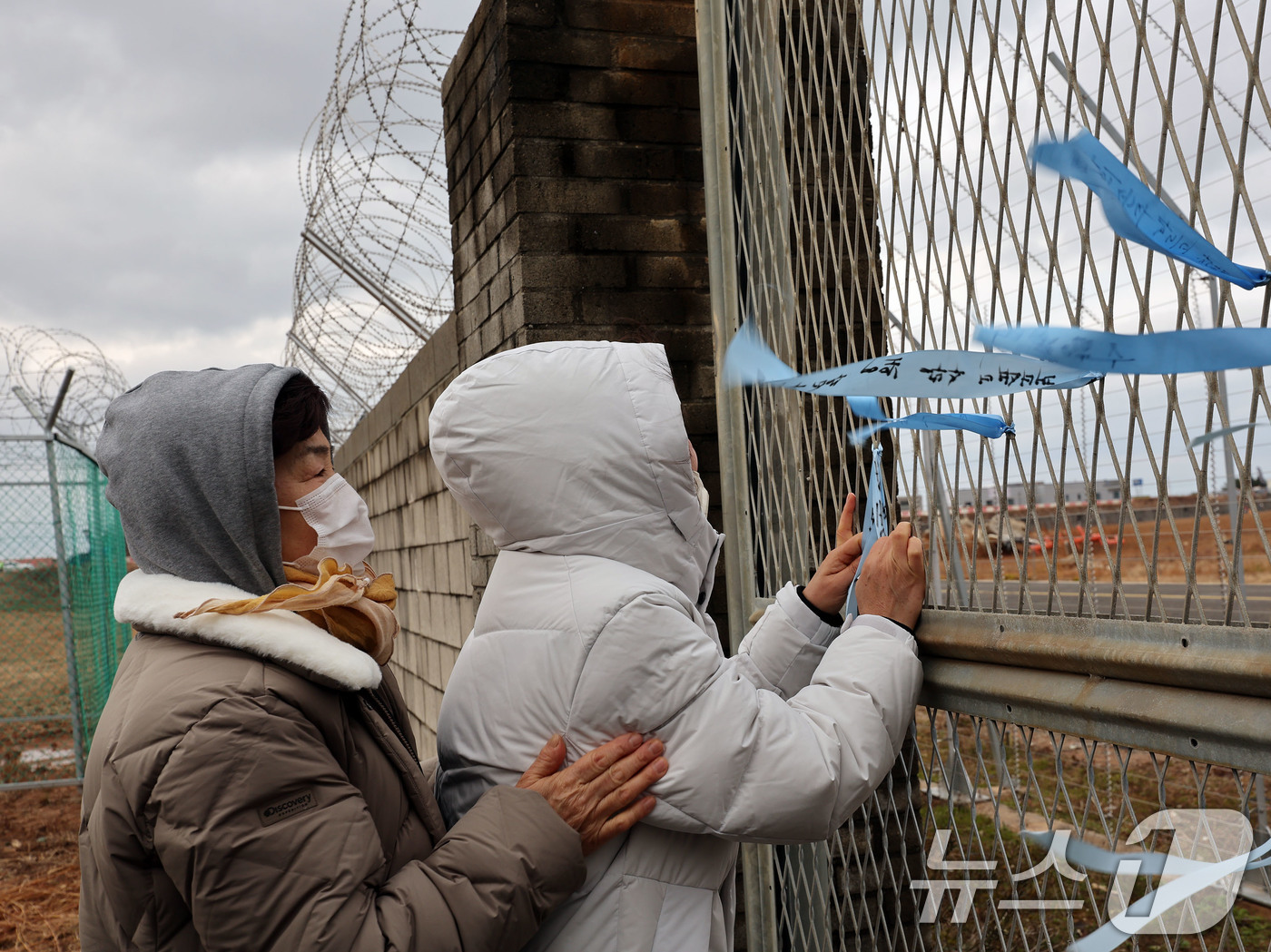 (무안=뉴스1) 박지현 기자 = 12·29 제주항공 여객기 참사 1주기를 앞둔 24일 전남 무안국제공항에서  유가족들이 활주로를 바라보며 추모 리본을 달고 있다.  2025.12. …