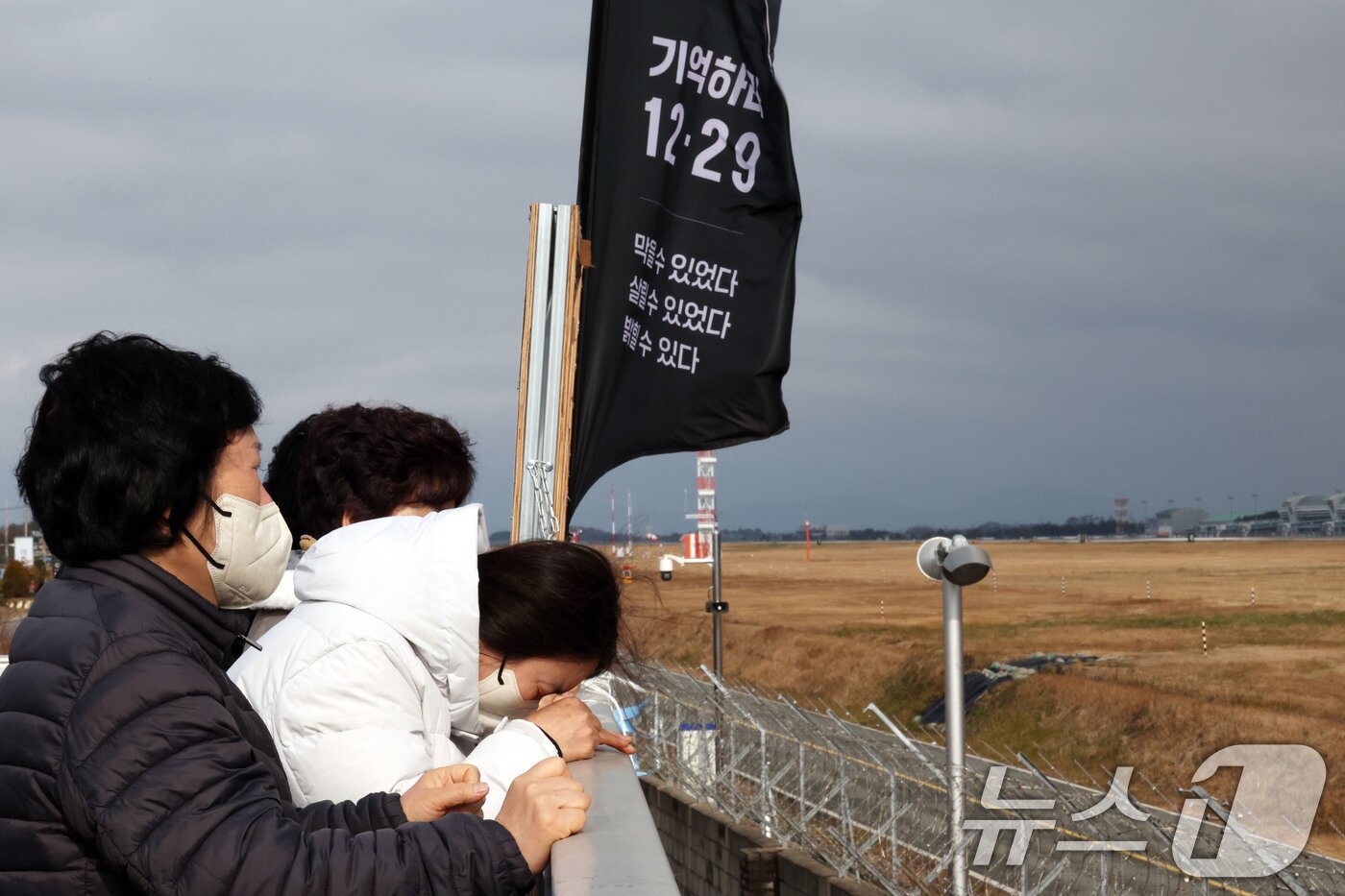 본문 이미지 - 12·29 제주항공 여객기 참사 1주기를 앞둔 24일 전남 무안국제공항에서 유족들이 공항 활주로를 바라보며 눈물짓고 있다. ⓒ News1 박지현 기자