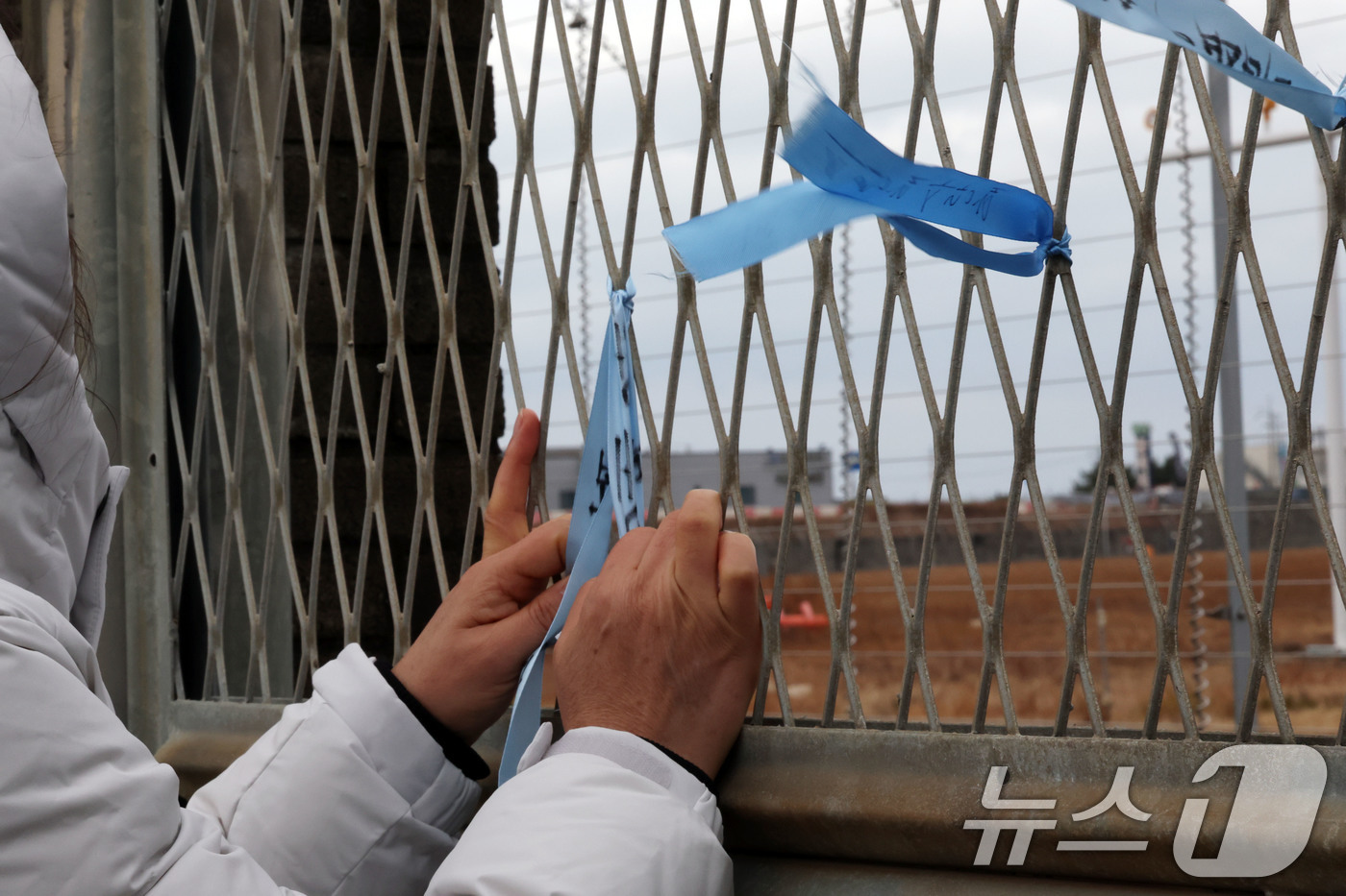 (무안=뉴스1) 박지현 기자 = 12·29 제주항공 여객기 참사 1주기를 앞둔 24일 전남 무안국제공항에서 유가족이 추모 리본을 작성해 달고 있다. 2025.12.24/뉴스1