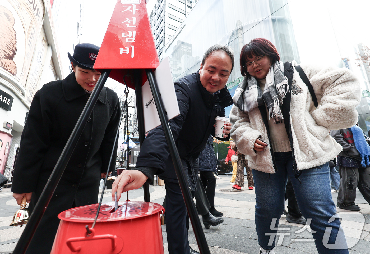 (서울=뉴스1) 김민지 기자 = 크리스마스 이브인 24일 오후 서울 중구 명동거리에서 아버지와 딸이 구세군 냄비에 온정을 보태고 있다. 2025.12.24/뉴스1