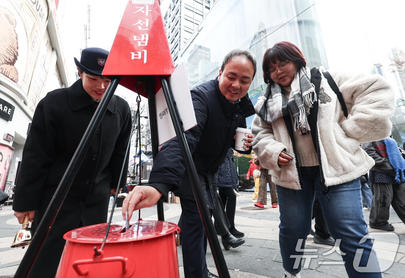본문 이미지 - 크리스마스 이브인 24일 오후 서울 중구 명동거리에서 아버지와 딸이 구세군 냄비에 온정을 보태고 있다. 2025.12.24/뉴스1 ⓒ News1 김민지 기자