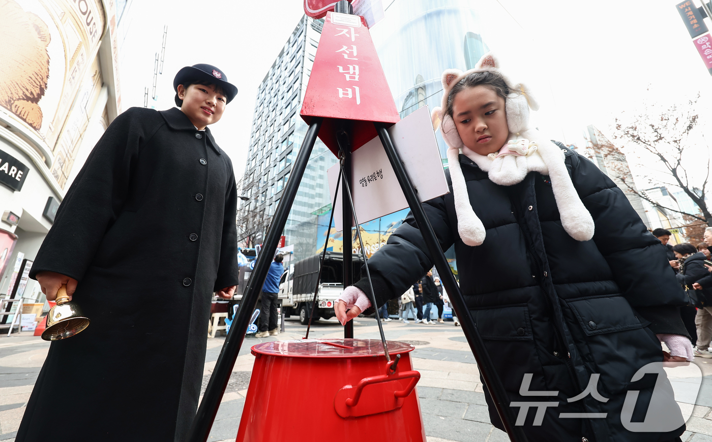(서울=뉴스1) 김민지 기자 = 크리스마스 이브인 24일 오후 서울 중구 명동거리에서 한 어린이가 구세군 냄비에 온정을 보태고 있다. 2025.12.24/뉴스1