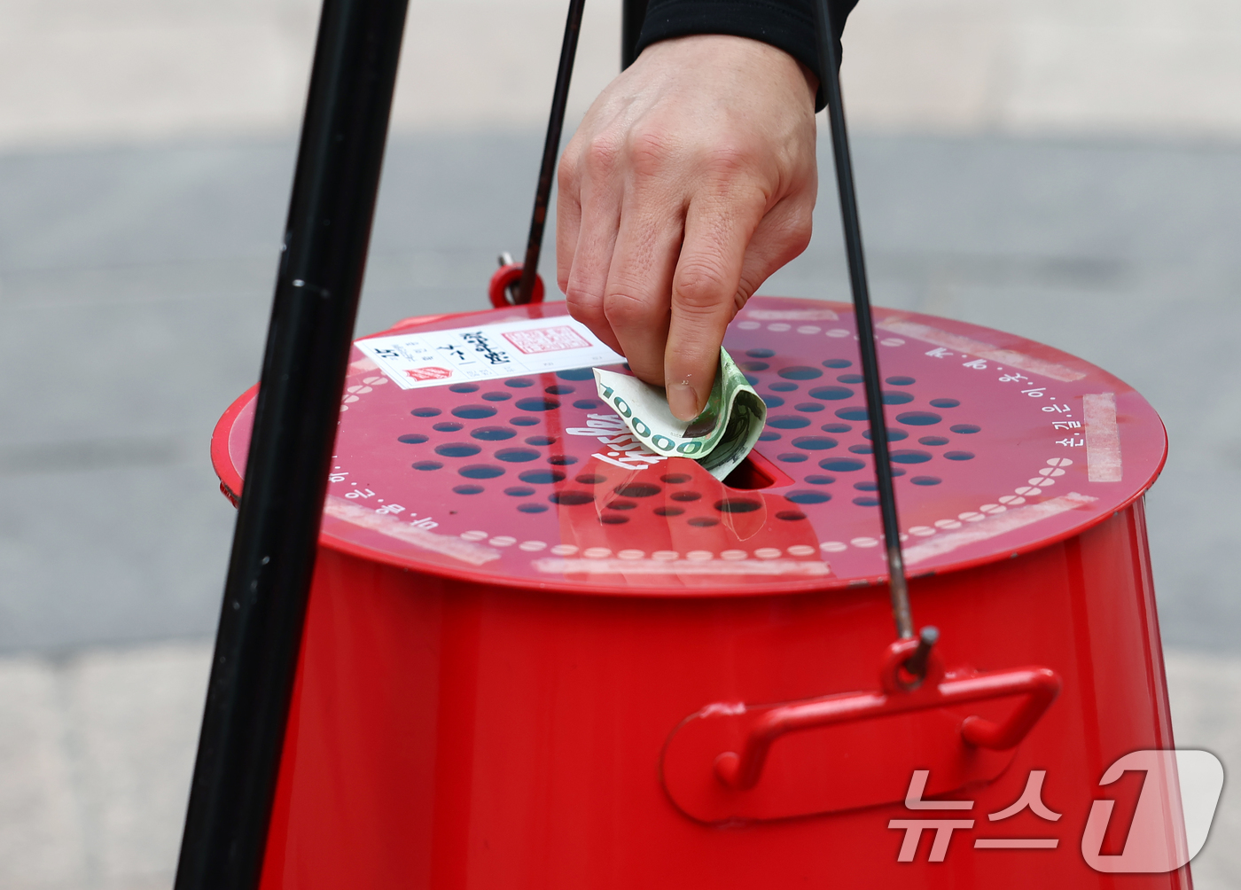 (서울=뉴스1) 김민지 기자 = 크리스마스 이브인 24일 오후 서울 중구 명동거리에서 한 시민이 구세군 냄비에 온정을 보태고 있다. 2025.12.24/뉴스1