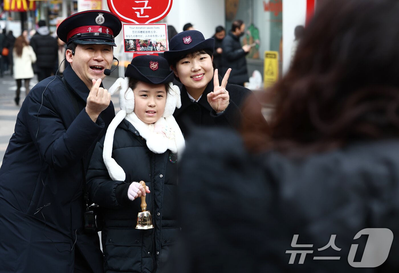 본문 이미지 - 크리스마스 이브인 24일 오후 서울 중구 명동거리에서 한 어린이가 구세군 자선냄비에 기부한 후 사진을 찍고 있다. 2025.12.24/뉴스1 ⓒ News1 김민지 기자