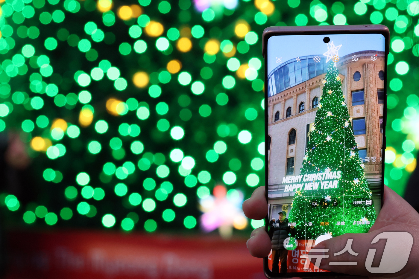 (서울=뉴스1) 황기선 기자 = 크리스마스 이브인 24일 오후 서울 중구 명동거리가 성탄절 분위기를 만끽하려는 외국인 관광객이 트리를 촬영하고 있다.  2025.12.24/뉴스1