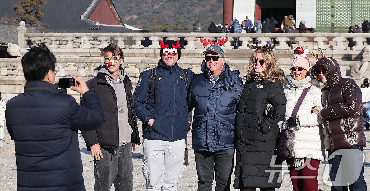 본문 이미지 - 크리스마스인 25일 서울 종로구 경복궁을 찾은 외국인 관광객들이 산타 장식을 두른 채 추억을 남기고 있다.  2025.12.25/뉴스1 ⓒ News1 김진환 기자