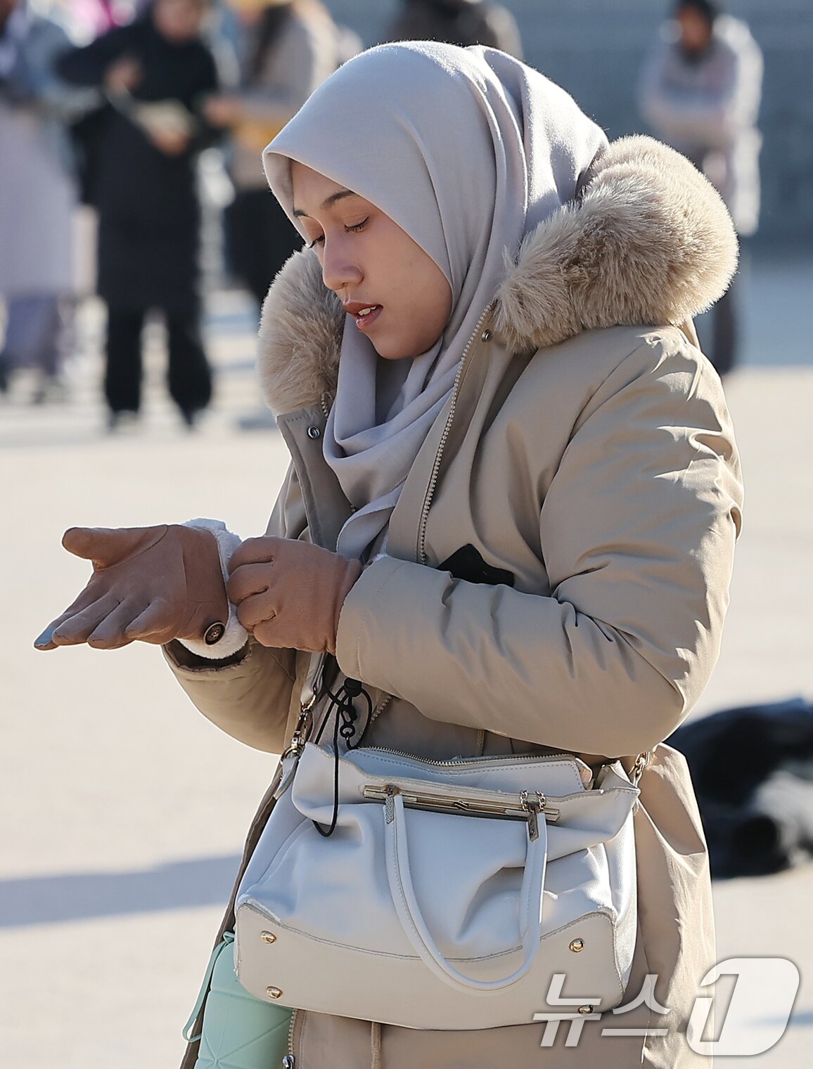 본문 이미지 - 서울과 경기에 한파주의보가 내려진 25일 서울 종로구 경복궁을 찾은 외국인 관광객이 강추위에 장갑을 끼며 이동하고 있다.  2025.12.25/뉴스1 ⓒ News1 김진환 기자