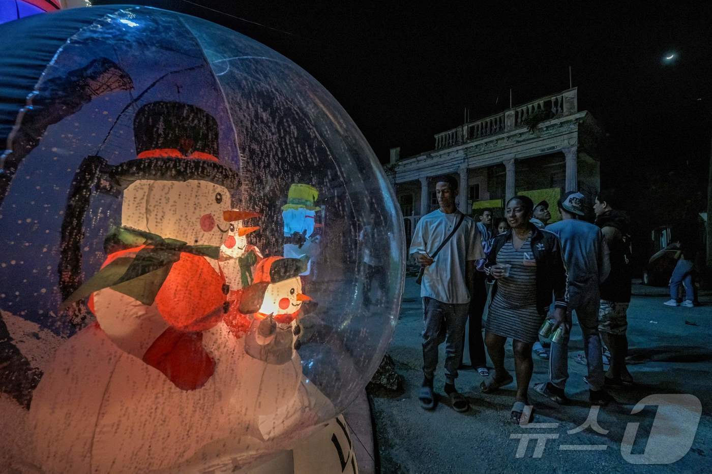 (하바나 AFP=뉴스1) 이정환 기자 = 25일(현지시간) 쿠바 하바나에서 일어난 정전 사태 중 주민들이 발전기를 돌려 산타클로스 풍선 장식에 불을 밝힌 집 주변에 모여 크리스마스 …