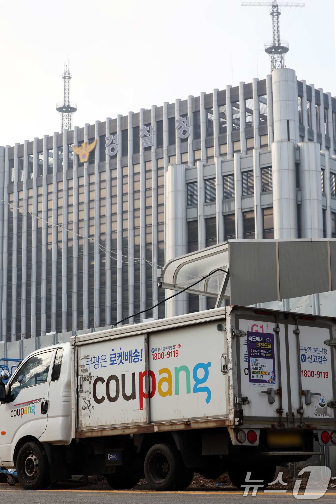 (서울=뉴스1) 황기선 기자 = 28일 서울 시내 한 쿠팡 물류센터 앞에 주차돼 있는 쿠팡카(쿠팡 배송트럭) 너머로 경찰청이 보이고 있다. 약 3300만 명의 고객 정보 유출 사태 …