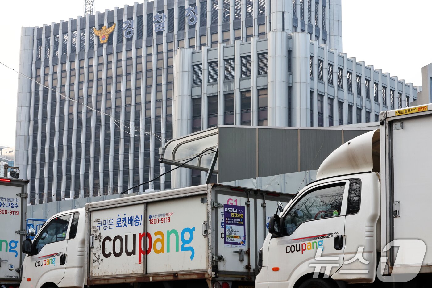 본문 이미지 - 28일 서울 시내 한 쿠팡 물류센터 앞에 주차돼 있는 쿠팡카(쿠팡 배송트럭) 너머로 경찰청이 보이고 있다. 약 3300만 명의 고객 정보 유출 사태를 빚은 쿠팡은 지난 26일 정부와의 협력을 통해 노트북 등을 조사했다고 주장 했지만 경찰은 "협의가 없었다＂고 반박에 나섰다. 2025.12.28/뉴스1 ⓒ News1 황기선 기자
