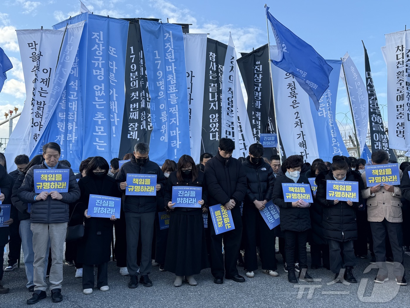 (무안=뉴스1) 김태성 기자 = 12·29 여객기 참사 1주기를 하루 앞둔 28일 오후 무안국제공항 외곽도로에서 만장행진을 한 참사 유가족들과 시민들이 희생자들을 위해 묵념을 올리 …