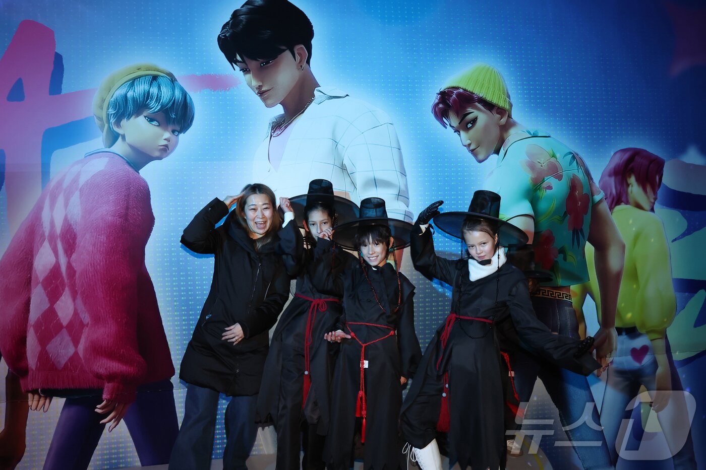 본문 이미지 - 경기 용인시 에버랜드 내 케이팝 데몬 헌터스 팝업존에서 메기 강(Maggie Kang) 감독(왼쪽)이 저승사자 의상을 차려 입은 관람객들과 함께 기념촬영하고 있다. ⓒ News1 장수영 기자