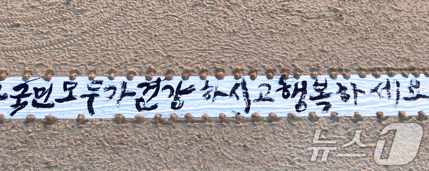(포항=뉴스1) 최창호 기자 = 독도 서예가 김동욱 씨가 26일 오전 경북 포항시 송도해수욕장 백사장에서 길이 50m 광목천에 2026년 병오년 한해도 국민의 행복을 기원하는 글귀 …