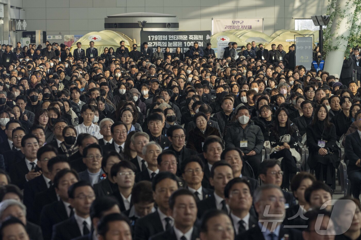 본문 이미지 - 12.29 제주항공 여객기 참사 1주기인 29일 오전 전남 무안국제공항에서 추모식이 엄수되고 있다. 추모식에 참석한 시민들이 침통한 표정으로 추모 행사를 바라보고 있다. 2025.12.29/뉴스1 ⓒ News1 사진공동취재단