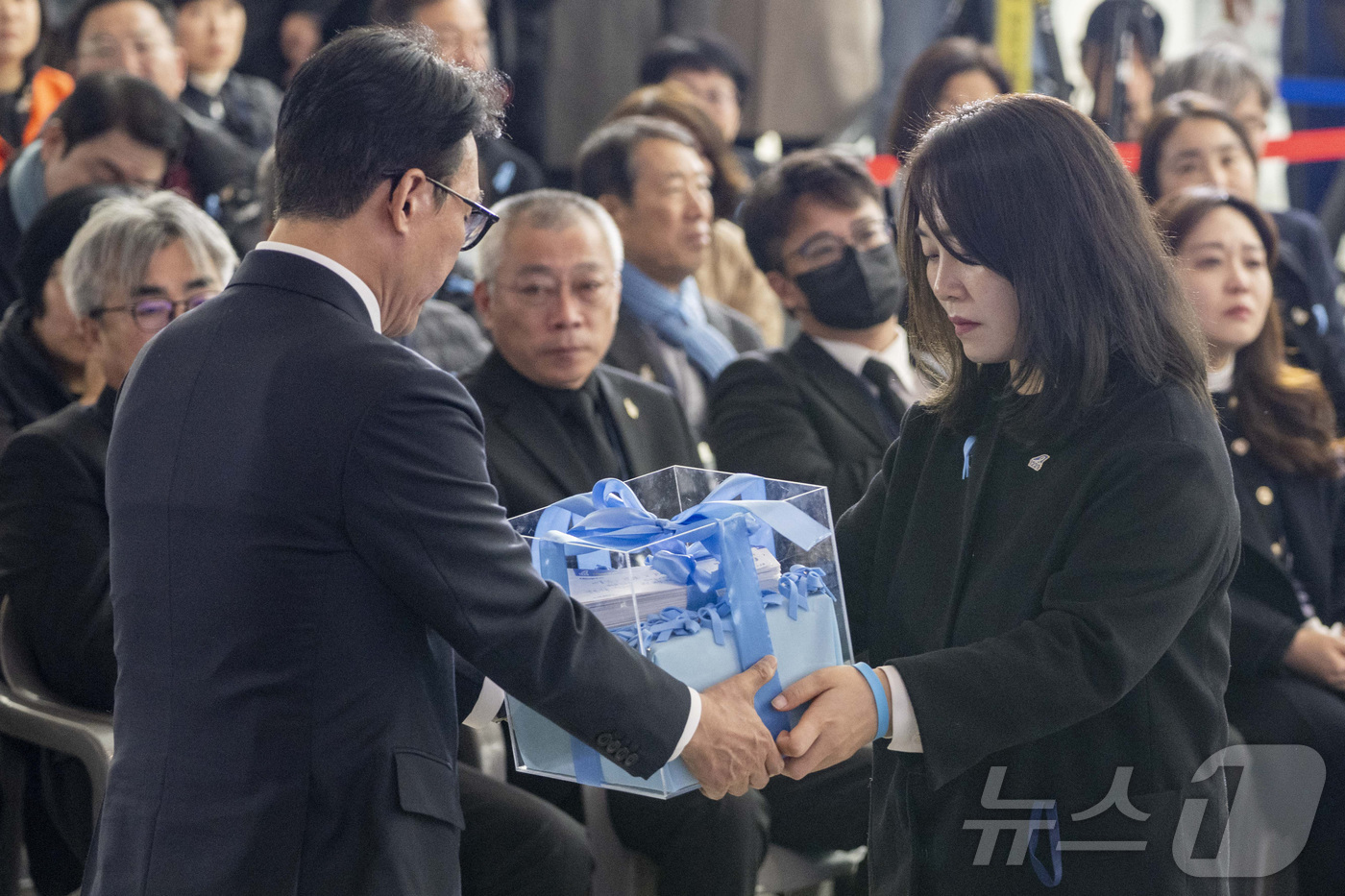 (무안=뉴스1) 사진공동취재단 = 김민석 국무총리가 29일 오전 무안국제공항에서 열린 12.29 제주항공 여객기 참사 1주기 추모식에서 김유진 유가족협의체 대표로부터 유가족들의 염 …