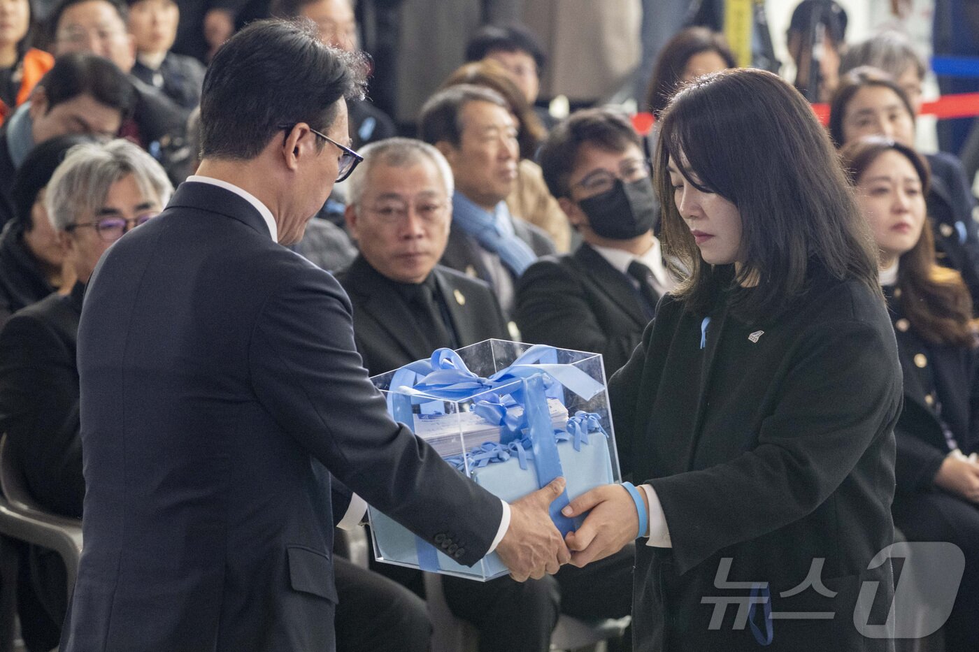 본문 이미지 - 김민석 국무총리가 29일 오전 무안국제공항에서 열린 12.29 제주항공 여객기 참사 1주기 추모식에서 김유진 유가족협의체 대표로부터 유가족들의 염원이 담긴 편지함을 전달받고 있다. 2025.12.29/뉴스1 ⓒ News1 사진공동취재단