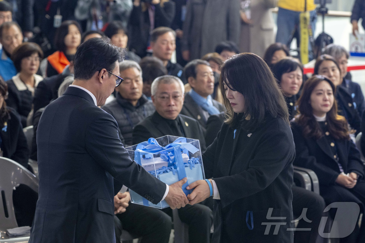 (무안=뉴스1) 사진공동취재단 = 김민석 국무총리가 29일 오전 무안국제공항에서 열린 12.29 제주항공 여객기 참사 1주기 추모식에서 김유진 유가족협의체 대표로부터 유가족들의 염 …