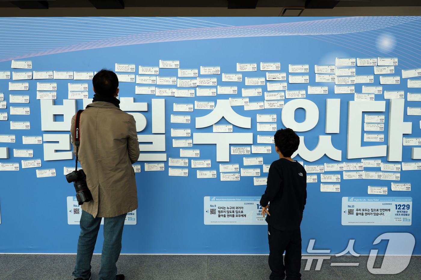 (무안=뉴스1) 박지현 기자 = 12·29 여객기 참사 1주기인 29일 전남 무안국제공항 내 추모의벽에서 시민들이 탑승권 형식의 추모메시지를 읽으며 추모하고 있다.  2025.12 …