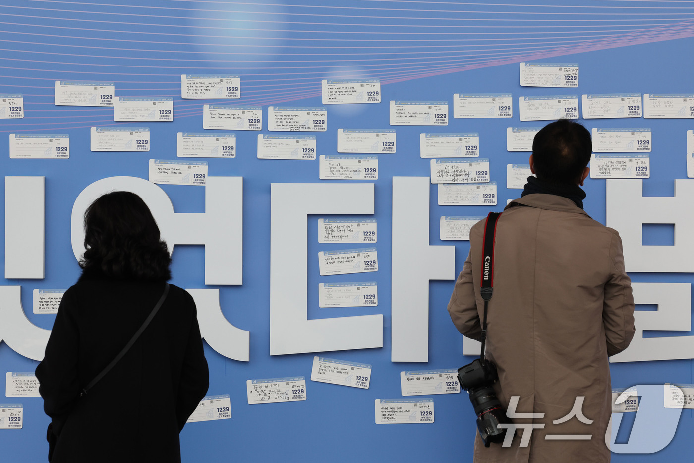 (무안=뉴스1) 박지현 기자 = 12·29 여객기 참사 1주기인 29일 전남 무안국제공항 내 추모의벽에서 시민들이 탑승권 형식의 추모메시지를 살펴보고 있다.  2025.12.29/ …