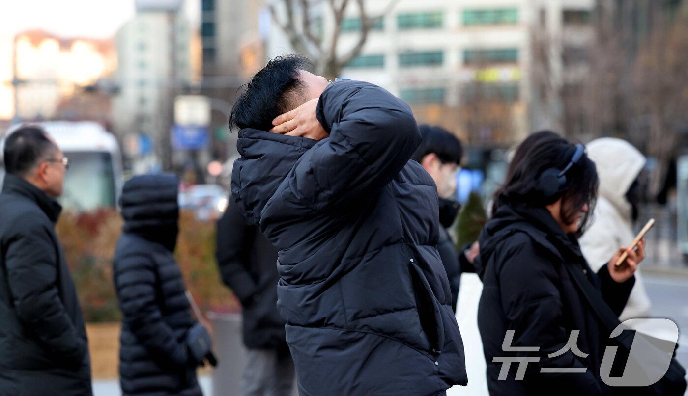 본문 이미지 - 전국 대부분 기온이 영하권의 추운 날씨를 보인 3일 서울 종로구 광화문네거리에서 두터운 옷차림을 한 시민이 차가워진 귀를 녹이고 있다. 2025.12.3/뉴스1 ⓒ News1 이호윤 기자