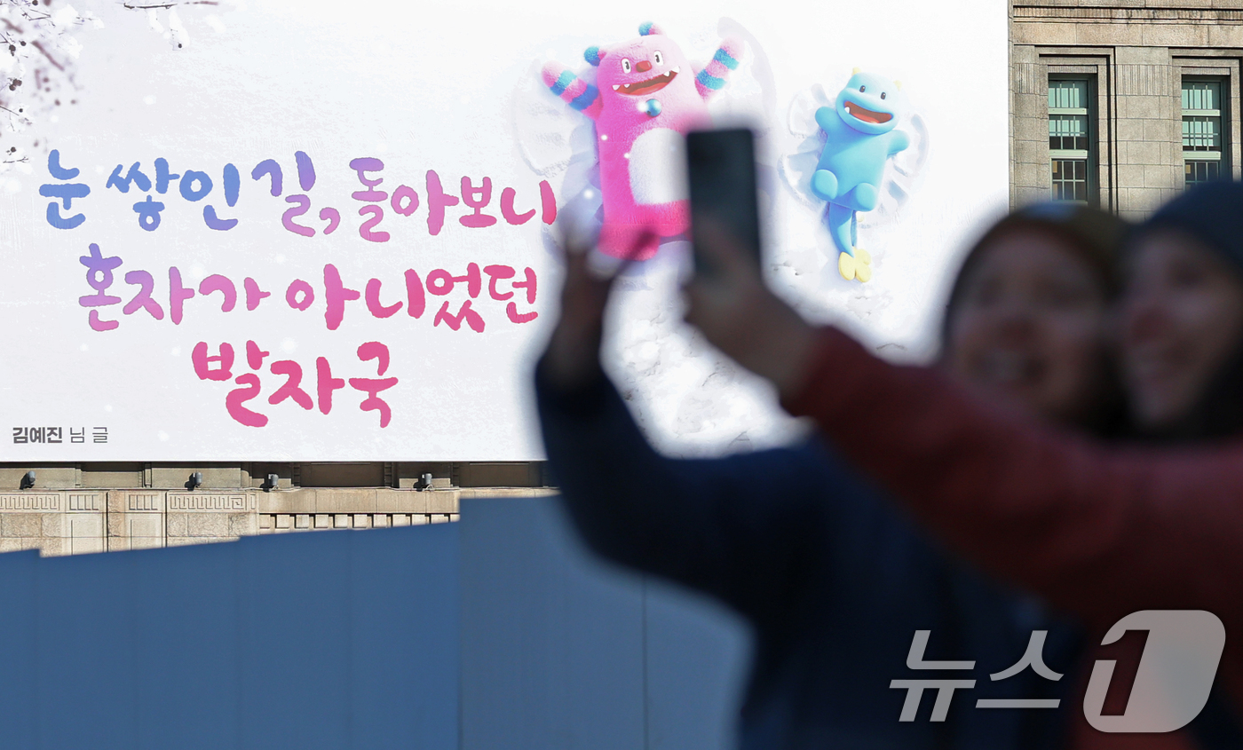 (서울=뉴스1) 오대일 기자 = 3일 서울광장을 찾은 외국인 관광객들이 겨울편으로 새단장한 서울꿈새김판 앞에서 기념촬영을 하고 있다.'겨울의 추위를 잊게 해주는 따뜻하고 희망찬 글 …