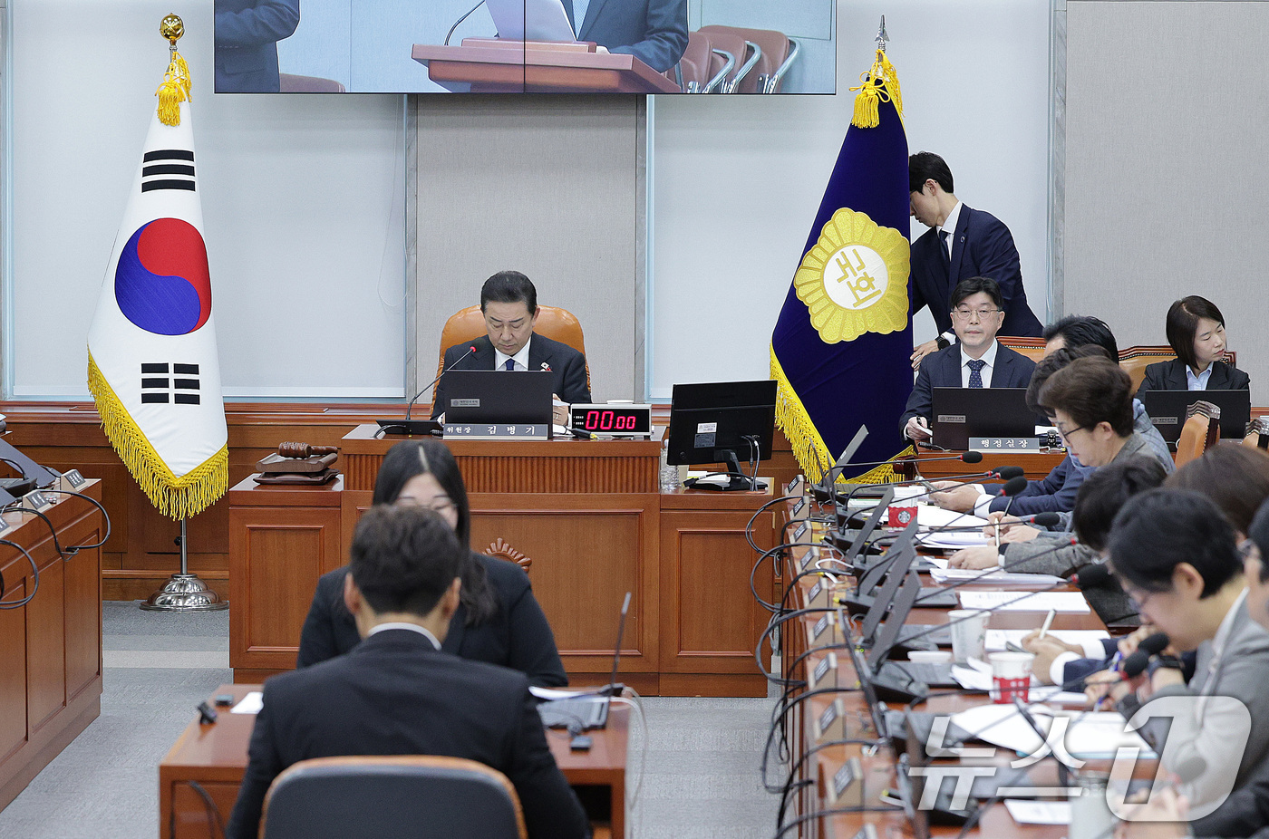 (서울=뉴스1) 신웅수 기자 = 3일 서울 여의도 국회에서 열린 국회운영위원회에서 전체회의에서 방호 직원들이 김병기 위원장 뒤쪽 공간으로 이동하지 못하도록 국회 깃발을 이동해 통로 …