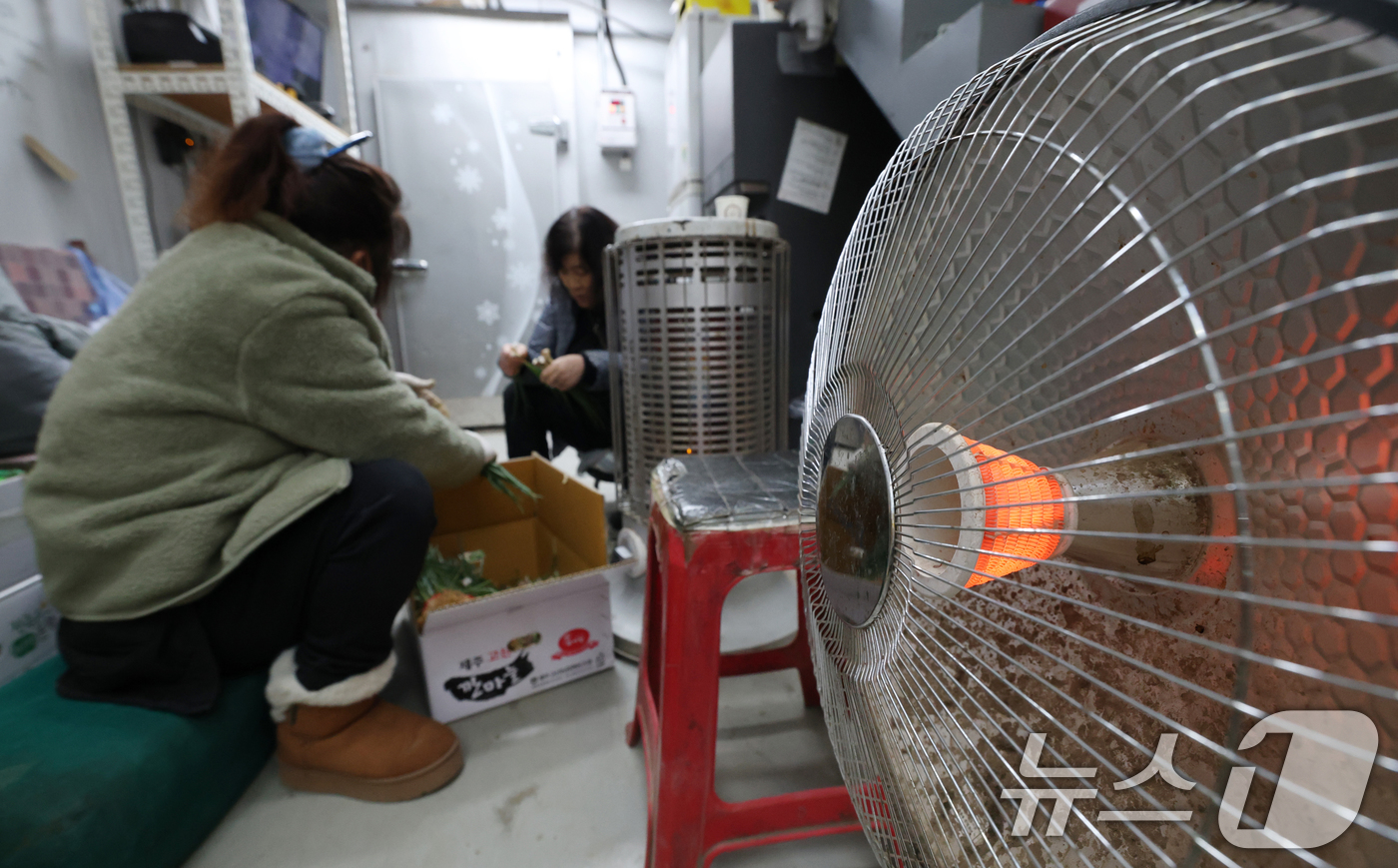 (수원=뉴스1) 김영운 기자 = 올겨울 첫 한파특보가 내려진 3일 경기 수원시 권선구 수원농수산물도매시장 채소동에서 상인들이 전기난로에 몸을 녹이며 쪽파를 다듬고 있다. 2025. …