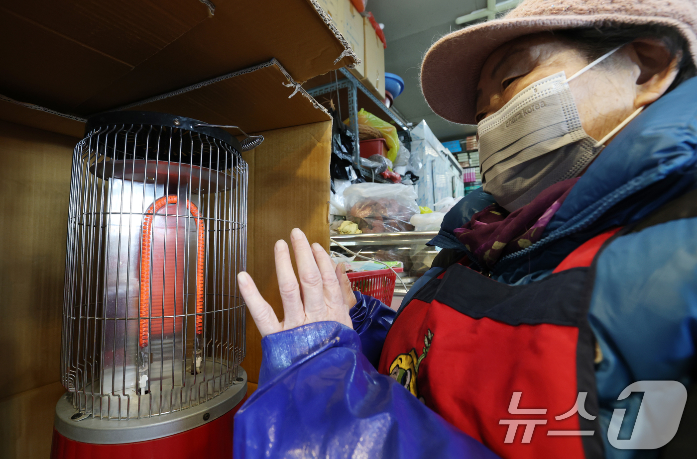 (수원=뉴스1) 김영운 기자 = 올겨울 첫 한파특보가 내려진 3일 경기 수원시 팔달구 지동시장에서 상인들이 전기난로에 몸을 녹이고 있다. 2025.12.3/뉴스1