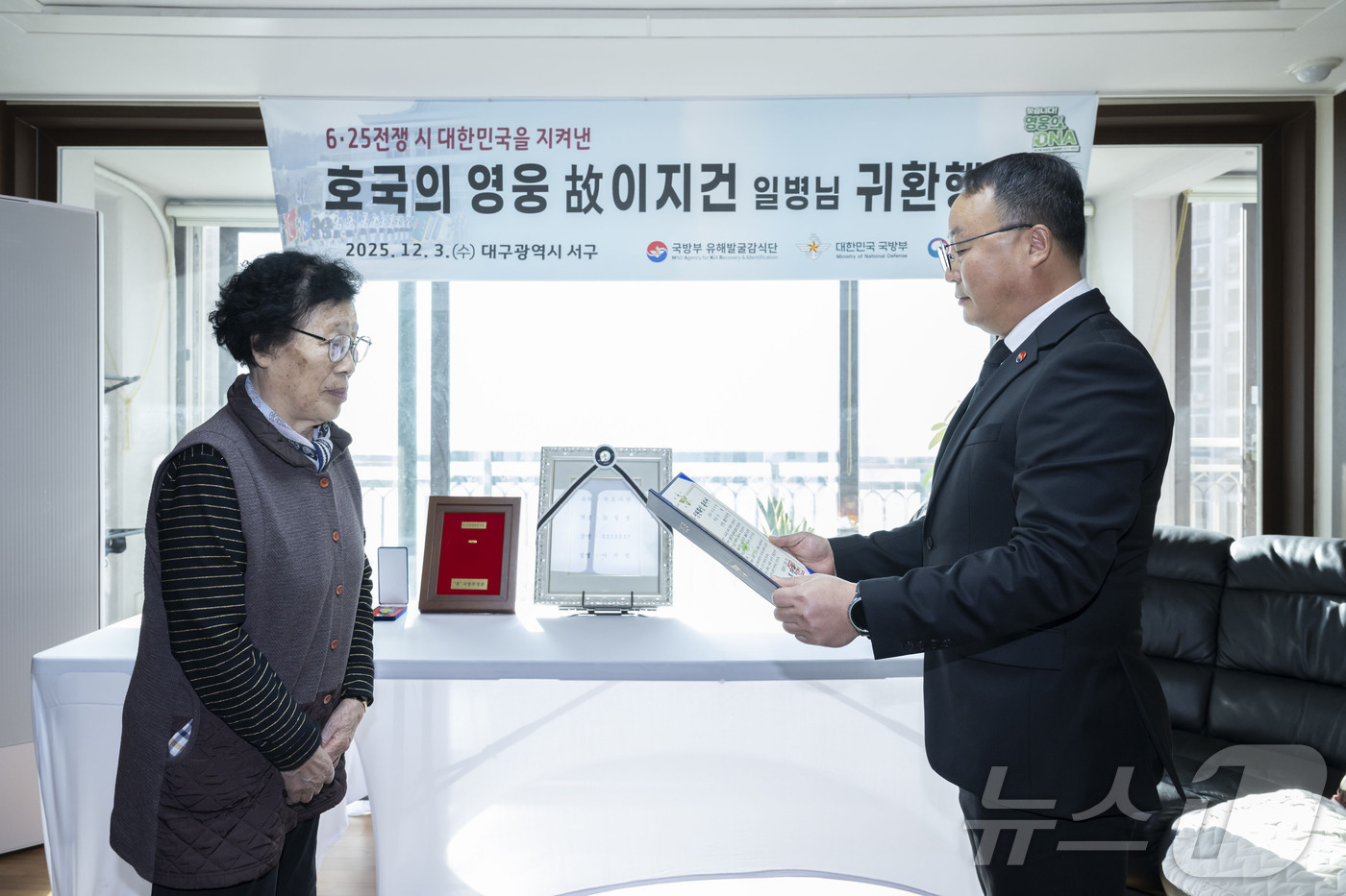(서울=뉴스1) = 조해학 국방부유해발굴감식단장 직무대리가 3일 대구광역시 서구 유가족의 자택에서 열린 호국의 영웅 귀환 행사에서 故 이지건 일병의 첫째 딸인 이호분 씨에게 고인의 …