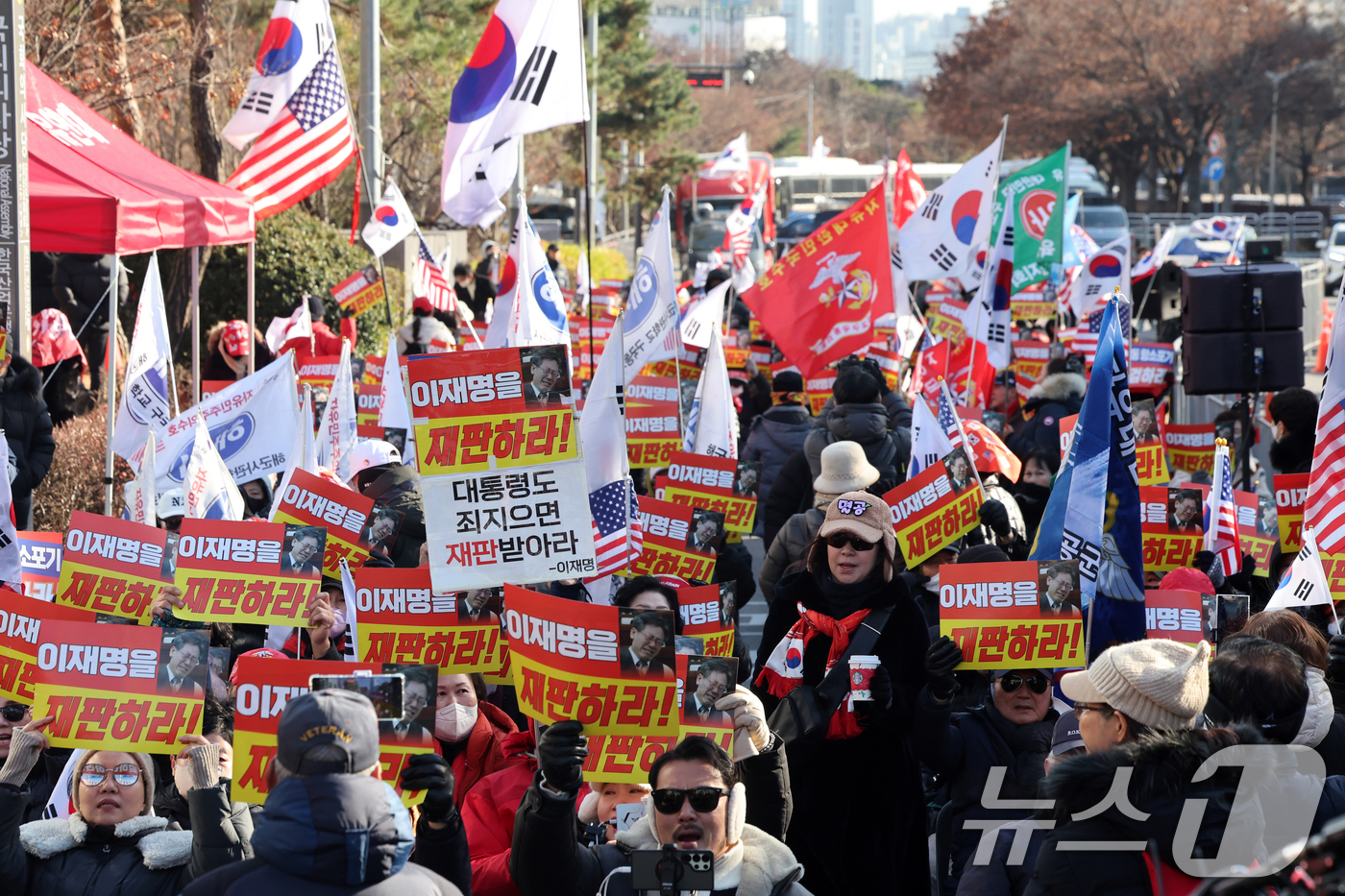 (서울=뉴스1) 황기선 기자 = 12·3 비상계엄 1년을 맞은 3일 오후 서울 영등포구 여의도 국회의사당역 앞에서 신자유연대 등 보수단체 회원들이 손팻말을 들고 이재명 대통령을 규 …