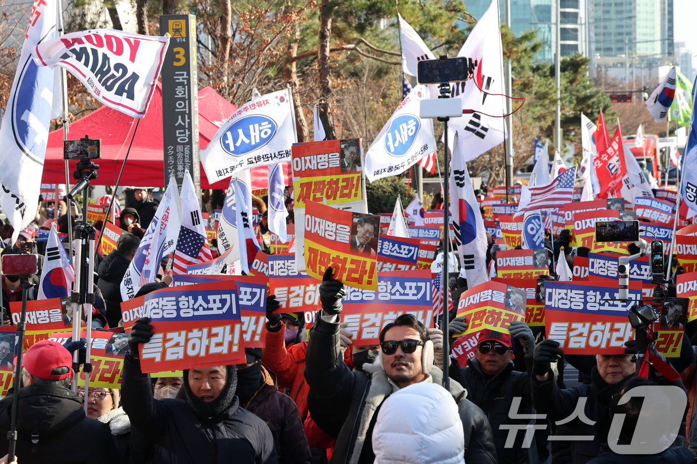 (서울=뉴스1) 황기선 기자 = 12·3 비상계엄 1년을 맞은 3일 오후 서울 영등포구 여의도 국회의사당역 앞에서 신자유연대 등 보수단체 회원들이 손팻말을 들고 이재명 대통령을 규 …