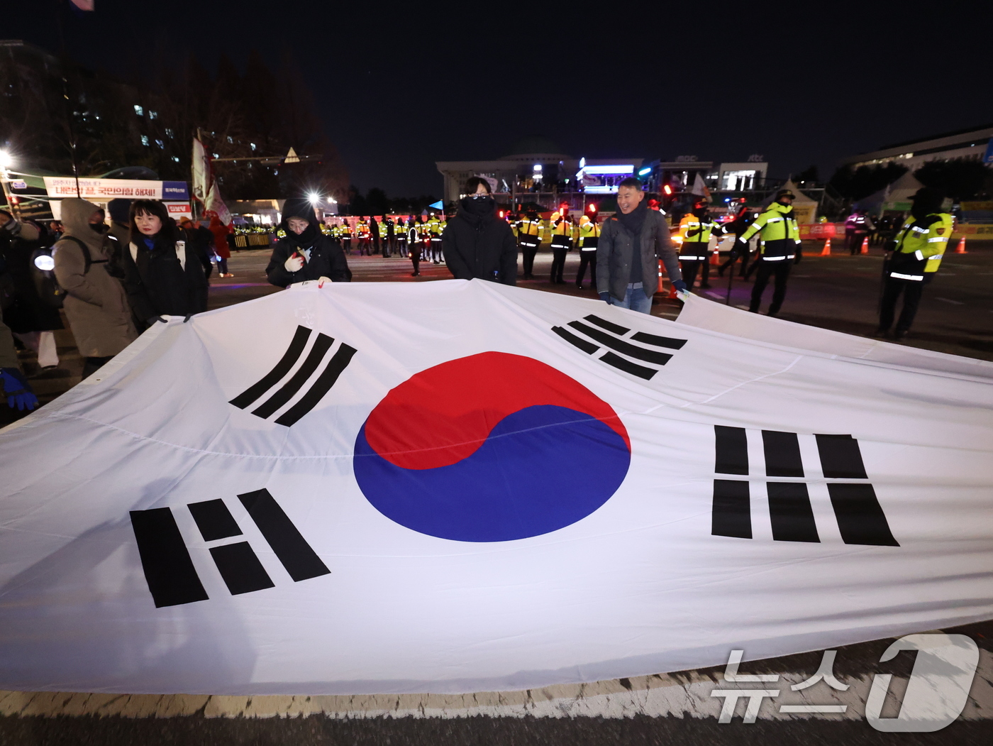 (서울=뉴스1) 박지혜 기자 = 12·3 비상계엄 1년을 맞은 3일 서울 여의도 국회 앞에서 '12·3 내란외환 청산과 종식, 사회대개혁 시민대행진'에 참여한 시민들이 태극기를 펼 …