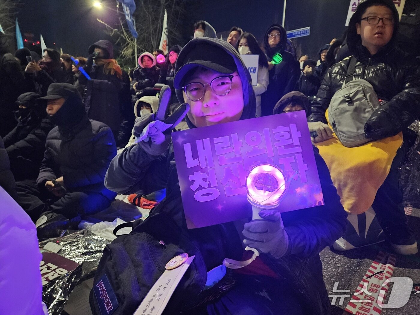 본문 이미지 - 3일 여의도 국회 앞에서 열린 시민대행진에 참석한 30대 전재현 씨가 응원봉과 피켓을 들고 V자 포즈를 취하고 있다. 2025.12.03/ⓒ 뉴스1 유채연 기자