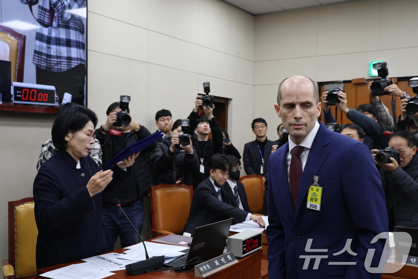 본문 이미지 - 해롤드 로저스 쿠팡 임시대표가 30일 서울 여의도 국회에서 열린 제430회국회(임시회) 쿠팡 침해사고 및 개인정보 유출, 불공정 거래, 노동환경 실태 파악과 재발방지 대책 마련을 위한 연석 청문회에 출석해 선서문을 최민희 위원장에게 전달하고 있다. 2025.12.30/뉴스1 ⓒ News1 이승배 기자