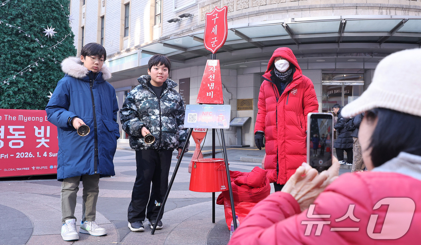 (서울=뉴스1) 박지혜 기자 = 자선냄비 모금 행사 종료를 하루 앞둔 30일 서울 중구 명동거리에서 기부를 마친 어린이들이 자선냄비 앞에서 기념촬영을 하고 있다.구세군 자선냄비 모 …