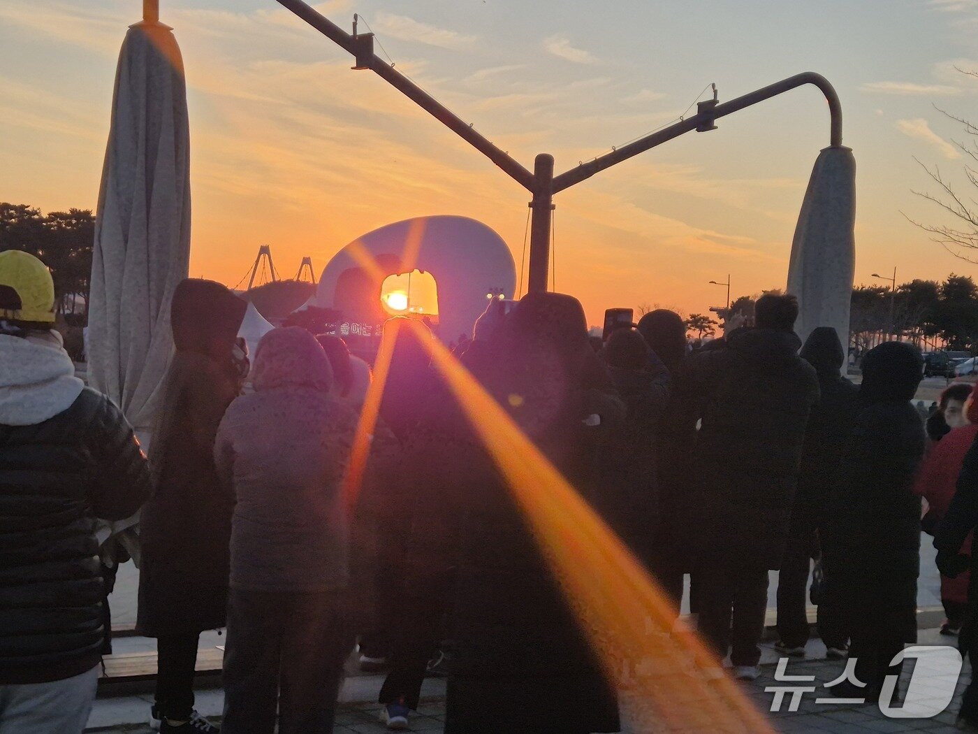 본문 이미지 -  31일 오후 지는 해가 인천 서구 아라빛섬정서진광장 조형물에 걸려있다/뉴스1