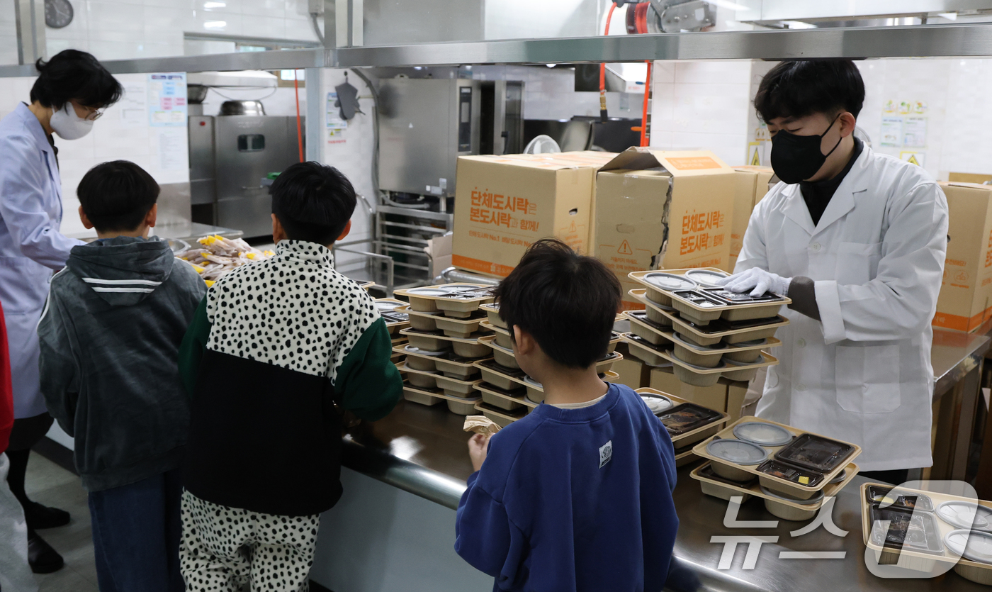 (대전=뉴스1) 김기태 기자 = 학교 급식·돌봄 업무 등에 종사하는 비정규직 노동자들이 총파업에 돌입한 4일 대전의 한 초등학교에서 어린이들이 도시락을 받고 있다. 2025.12. …