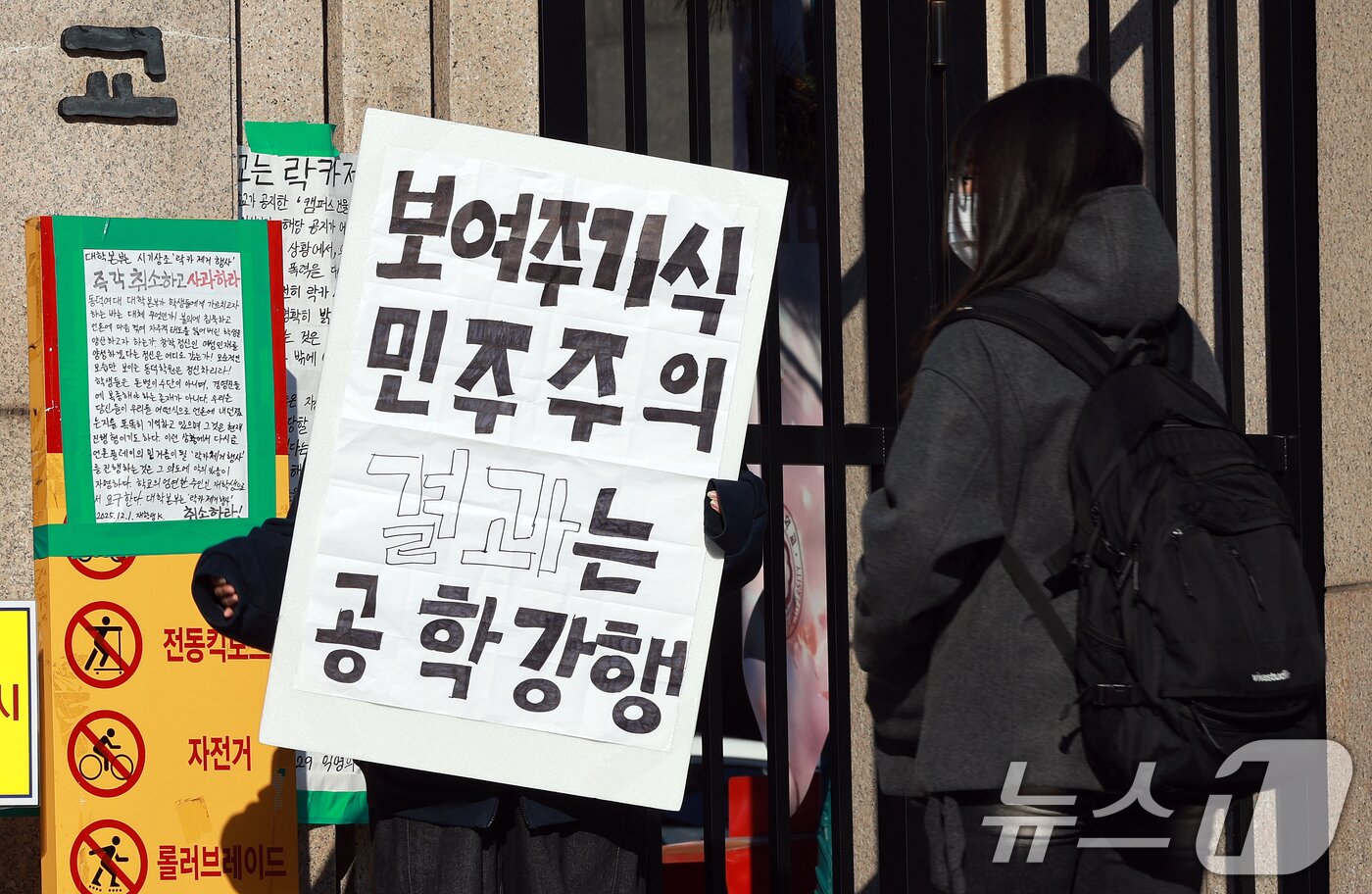 본문 이미지 - 4일 성북구 동덕여자대학교에서 한 학생이 공학반대 1인시위를 하고 있다. 동덕여자대학교와 학생들은 이날 캠퍼스 건물 공학 반대 항의 래커 제거 행사와 공학전환 강행 반대 시위를 각각 계획예정이었으나 동덕여대를 겨냥한 흉기난동 예고 글이 인터넷에 올라오면서 두 일정을 잠정 연기했다. 2025.12.4/뉴스1 ⓒ News1 이호윤 기자