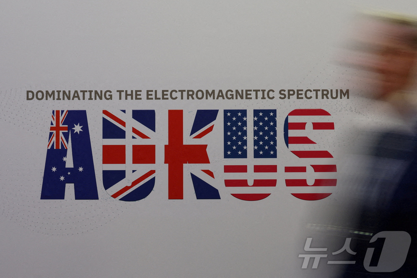 (시드니 로이터=뉴스1) 강민경 기자 = 호주 시드니에서 열린 인도태평양 국제해양전시회 첫날인 11월 4일 한 행인이 오커스 로고 앞을 지나가고 있다. 오커스는 미국과 영국, 호주 …