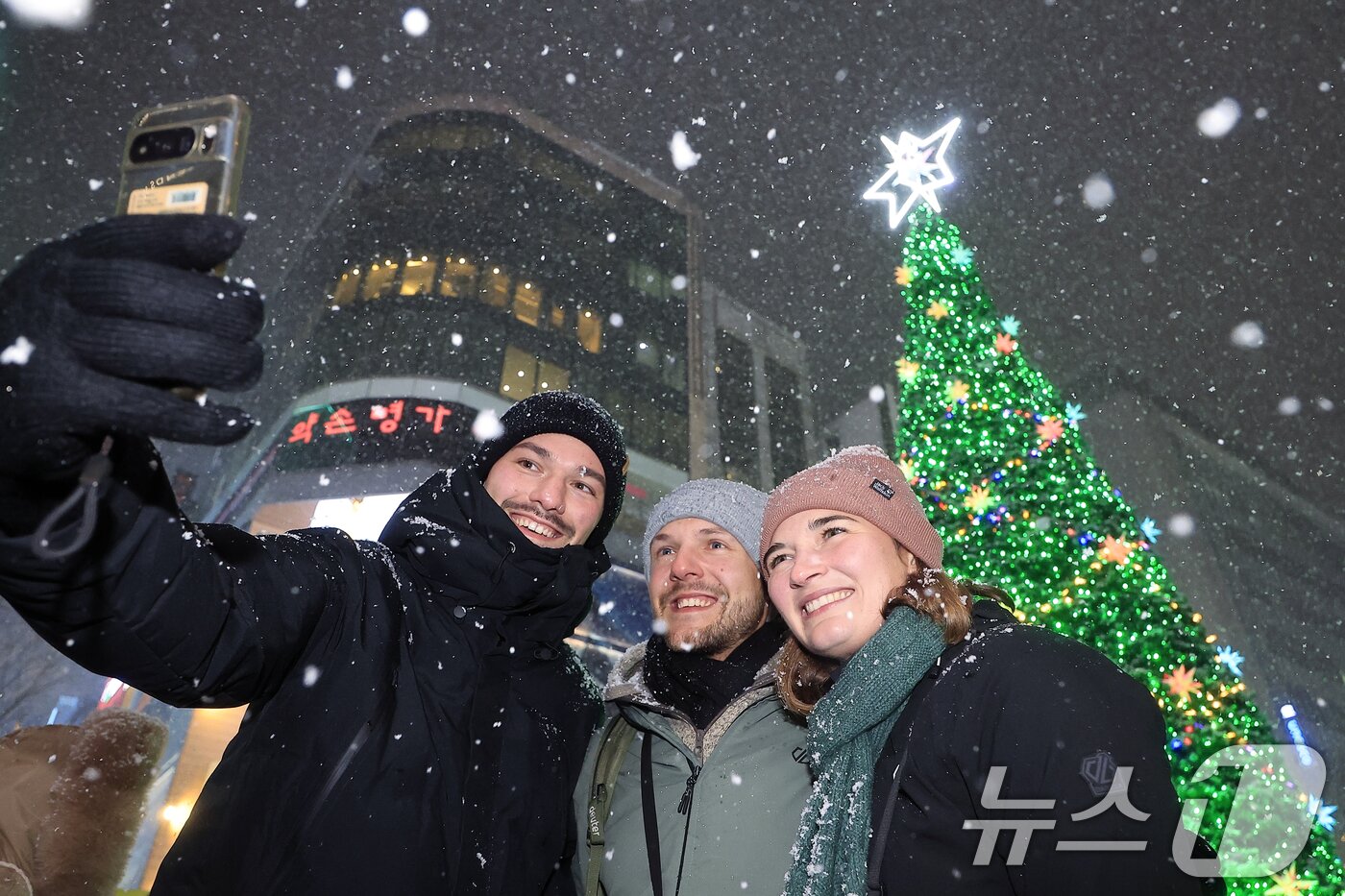 본문 이미지 - 첫눈이 내린 4일 오후 서울 중구 명동을 찾은 관광객들이 내리는 눈을 맞으며 즐거워하고 있다. 기상청은 &#34;퇴근 시간대 강한 눈이 내릴 가능성이 크다＂며 동네 예보와 실시간 날씨를 확인할 것을 당부했다. 2025.12.4/뉴스1 ⓒ News1 박정호 기자