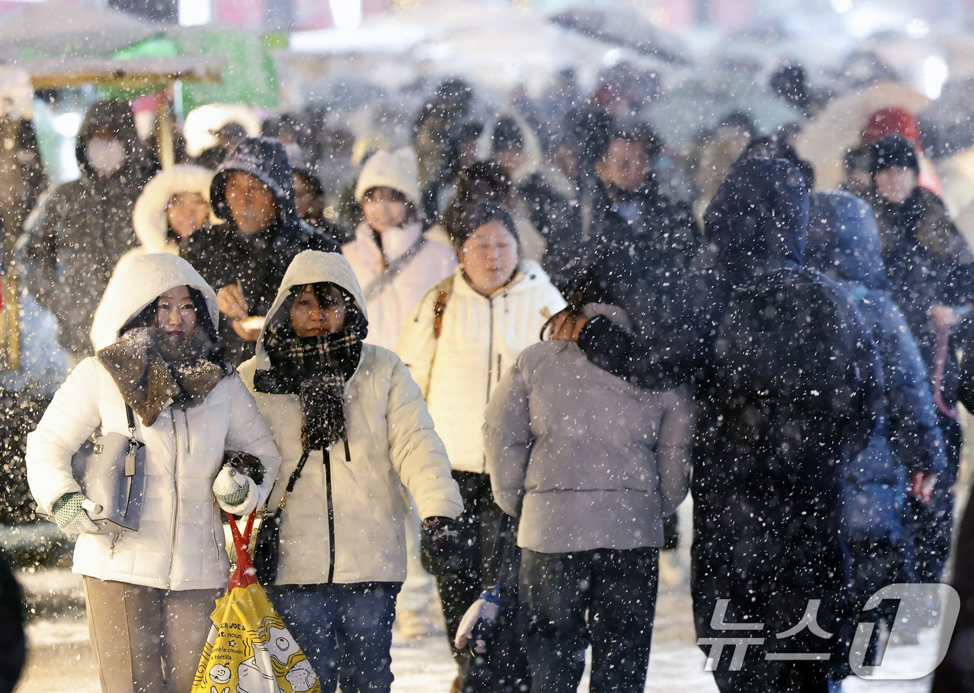 (서울=뉴스1) 박정호 기자 = 첫눈이 내린 4일 오후 서울 중구 명동을 찾은 관광객들이 내리는 눈을 맞으며 거리를 걷고 있다.기상청은 "퇴근 시간대 강한 눈이 내릴 가능성이 크다 …