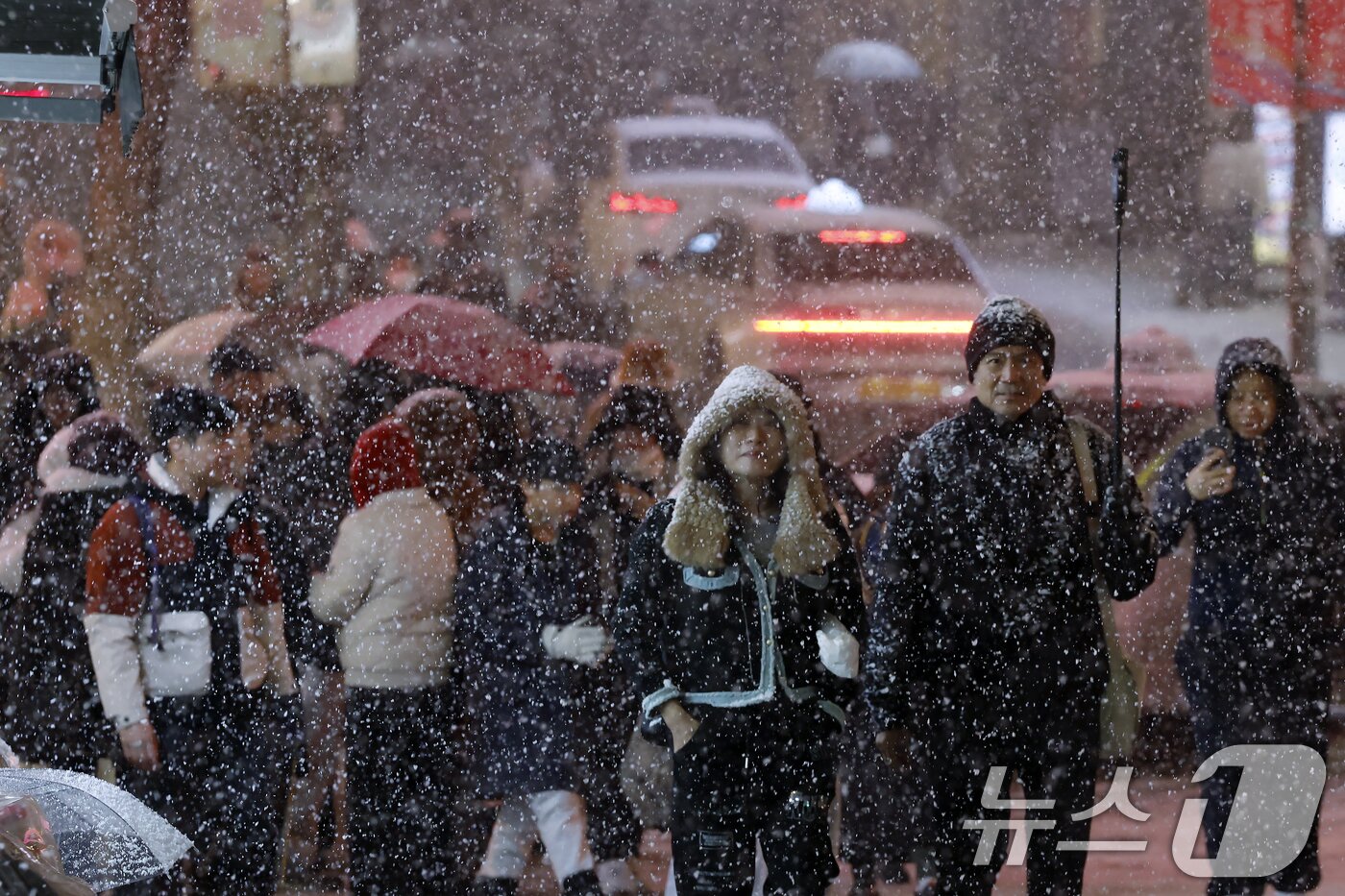 본문 이미지 - 첫눈이 내린 4일 오후 서울 중구 명동을 찾은 관광객들이 내리는 눈을 맞으며 즐거워하고 있다. 기상청은 &#34;퇴근 시간대 강한 눈이 내릴 가능성이 크다＂며 동네 예보와 실시간 날씨를 확인할 것을 당부했다. 2025.12.4/뉴스1 ⓒ News1 박정호 기자