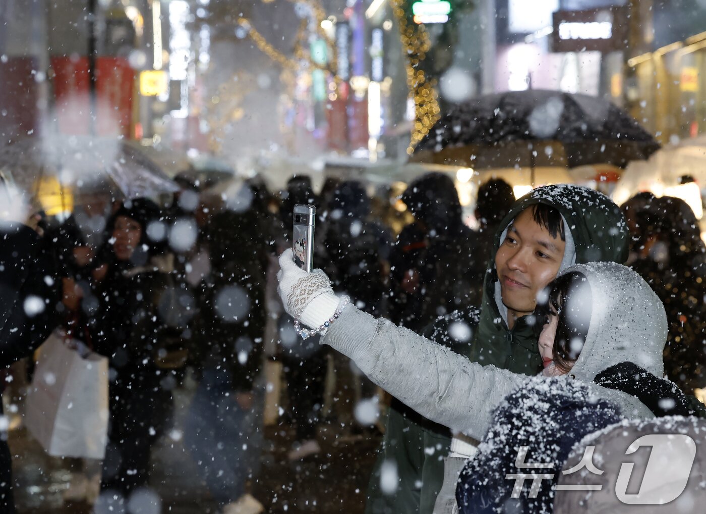 본문 이미지 - 첫눈이 내린 4일 오후 서울 중구 명동을 찾은 관광객들이 내리는 눈을 맞으며 즐거운 시간을 보내고 있다. 기상청은 &#34;퇴근 시간대 강한 눈이 내릴 가능성이 크다＂며 동네 예보와 실시간 날씨를 확인할 것을 당부했다. 2025.12.4/뉴스1 ⓒ News1 박정호 기자