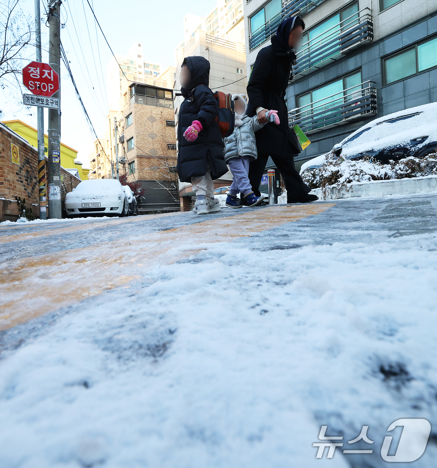 (서울=뉴스1) 오대일 기자 = 폭설 후 한파로 도로 곳곳이 얼어 붙은 5일 오전 서울 광진구에서 한 여성이 아이들과 빙판길을 걷고 있다.  2025.12.5/뉴스1
