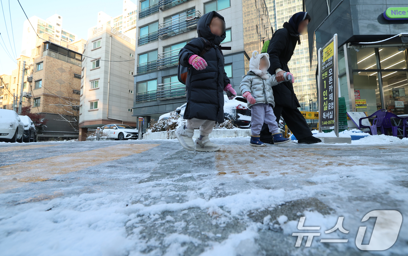 (서울=뉴스1) 오대일 기자 = 폭설 후 한파로 도로 곳곳이 얼어 붙은 5일 오전 서울 광진구에서 한 여성이 아이들과 빙판길을 걷고 있다.  2025.12.5/뉴스1
