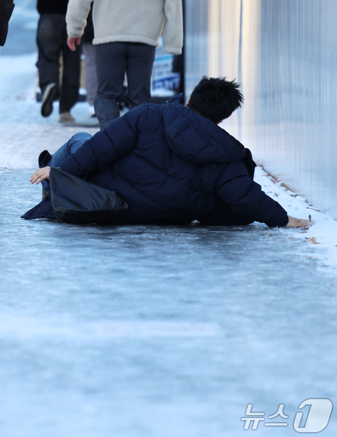 (서울=뉴스1) 구윤성 기자 = 폭설 후 한파로 도로 곳곳이 얼어 붙은 5일 오전 서울 광화문역 일대에서 한 시민이 빙판길에 미끄러져 넘어지고 있다.  2025.12.5/뉴스1
