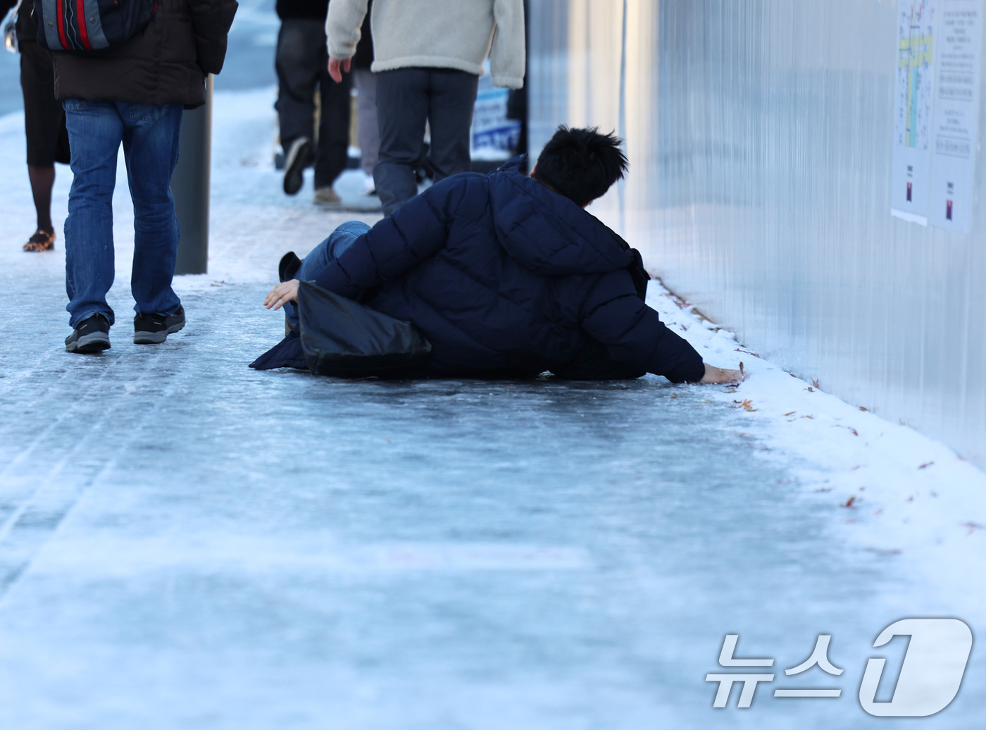 (서울=뉴스1) 구윤성 기자 = 폭설 후 한파로 도로 곳곳이 얼어붙은 5일 오전 서울 광화문역 일대에서 한 시민이 빙판길에 미끄러져 넘어지고 있다.  2025.12.5/뉴스1