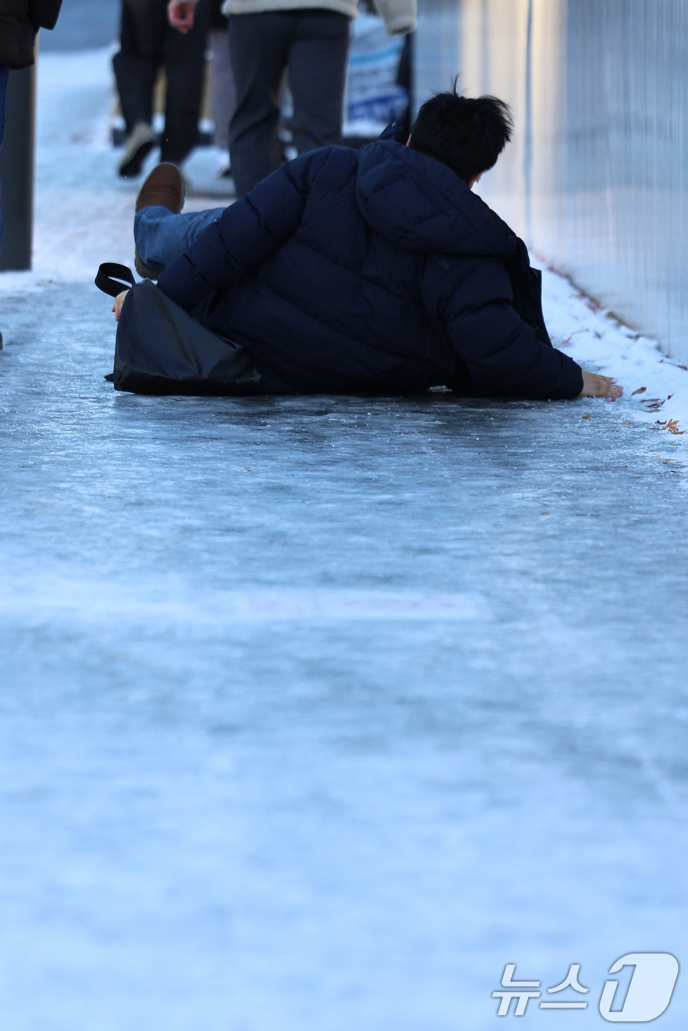 (서울=뉴스1) 구윤성 기자 = 폭설 후 한파로 도로 곳곳이 얼어붙은 5일 오전 서울 광화문역 일대에서 한 시민이 빙판길에 미끄러져 넘어지고 있다.  2025.12.5/뉴스1