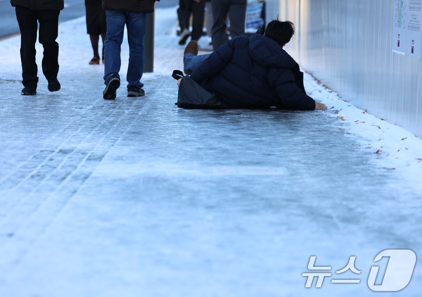 본문 이미지 - 폭설 후 한파로 도로 곳곳이 얼어붙은 5일 오전 서울 광화문역 일대에서 한 시민이 빙판길에 미끄러져 넘어지고 있다. 2025.12.5/뉴스1 ⓒ News1 구윤성 기자